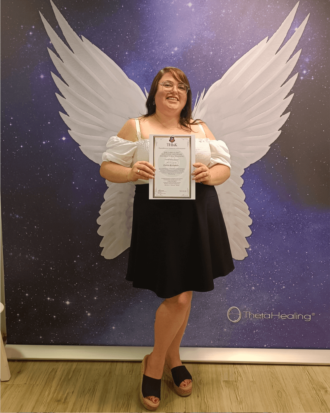 ילנה מצולמת עם תעודה רשמית של מורה לתטא הילינג